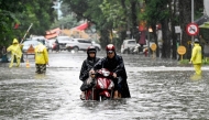 A man pushes his motorbike on a flooded street due to heavy rains caused by Tropical Storm Matmo in Hanoi on October 7, 2025. (Photo by Nhac Nguyen / AFP)