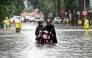 A man pushes his motorbike on a flooded street due to heavy rains caused by Tropical Storm Matmo in Hanoi on October 7, 2025. (Photo by Nhac Nguyen / AFP)