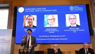 Heiner Linke (L), Chair of the Nobel Committee for Chemistry, explains a model as Hans Ellegren (C), Secretary General of The Royal Swedish Academy of Sciences, and Olof Ramstroem, Member of the Nobel Committe for Chemistry, listen in Stockholm, Sweden, on October 8, 2025. (Photo by Jonathan Nackstrand / AFP)