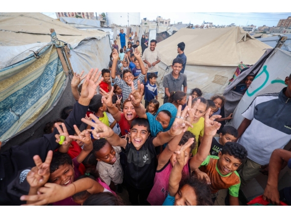 Palestinian children celebrate at a camp for displaced people in Nuseirat in the central Gaza Strip on October 9, 2025, following news of a new peace deal. (Photo by Eyad Baba / AFP)