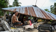 Men look for items in a collapsed house in Manay, in the province of Davao Oriental on October 11, 2025. (Photo by Jam Sta Rosa / AFP)
