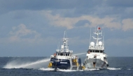This handout photo taken and released on October 12, 2025 by the Philippine Coast Guard shows a China Coast Guard ship (R) deploying water cannon as a Philippine Bureau of Fisheries vessel (L) is seen alongside during an incident near Thitu island in disputed waters of the South China Sea. Photo by Handout / Philippine Coast Guard (PCG) / AFP
