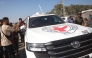 Palestinians gather on both sides of the road as International Red Cross vehicles arrive south of Deir al-Balah in the central Gaza Strip on October 13, 2025. (Photo by Bashar Taleb / AFP)
 