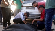 Friends and relatives mourn over the shrouded body of a man killed in an Israeli strike earlier, as he is brought to Deir al-Balah's Shuhada al-Aqsa hospital in the central Gaza Strip on October 19, 2025. (Photo by BASHAR TALEB / AFP)