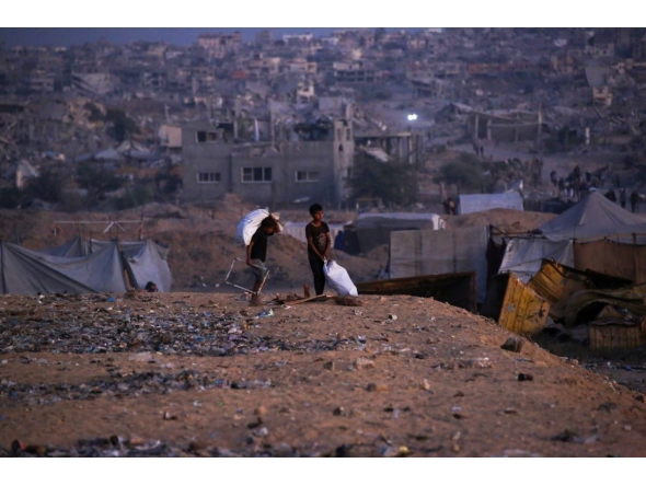 Palestinian children carry salvaged items in Khan Yunis, in the southern Gaza Strip on October 25, 2025. Photo by Bashar TALEB / AFP