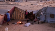Palestinians sit by the fire in their makeshift shelter in Khan Yunis, in the southern Gaza Strip on October 25, 2025. (Photo by Bashar Taleb / AFP)
