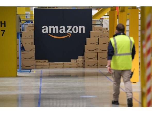 Files: An US giant Amazon employee passes by its logo on the opening day of the new distribution center in Augny, eastern France, on September 23, 2021. (Photo by Sebastien Bozon / AFP)