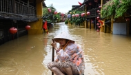 A woman rows a boat on a flooded street following heavy rains in Hoi An on October 30, 2025. (Photo by NHAC NGUYEN / AFP)