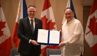 Philippines' Secretary of National Defence Gilberto Teodoro (R) with Canadian Minister of Defence David McGuinty hold their signed documents of the visiting forces agreement after their bilateral meeting in Manila on November 2, 2025. (Photo by Ted ALJIBE / AFP)