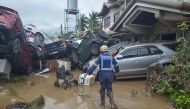 A rescuer walks past piled up cars washed away by floods at the height of Typhoon Kalmaegi in a subdivision of Cebu City in the central Philippines on November 4, 2025. Photo by Alan Tangcawan / AFP