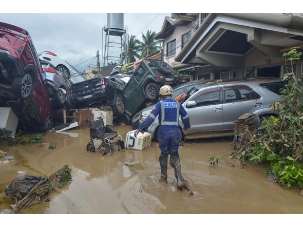 A rescuer walks past piled up cars washed away by floods at the height of Typhoon Kalmaegi in a subdivision of Cebu City in the central Philippines on November 4, 2025. (Photo by Alan Tangcawan / AFP)