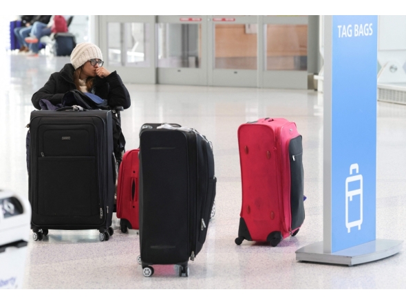 A traveler waits with her luggage at Newark Liberty International Airport in Newark, New Jersey, on November 7, 2025. (Photo by Timothy A. Clary / AFP)