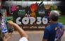 A tourist poses for a picture with COP30 mascot inside the Estacao das Docas, a tourist port area in Belem, Para State, Brazil on November 7, 2025. The COP30 UN Climate Change Conference takes place from November 10 to 21, in Belem, Para state, Brazil. (Photo by MAURO PIMENTEL / AFP)

