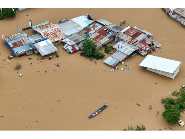 Aerial photo shows a resident paddles his boat in the flood waters past inundated houses in Tuguegarao City, Cagayan province, north of Manila on November 10, 2025. (Photo by John Dimain / AFP)