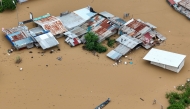 Aerial photo shows a resident paddles his boat in the flood waters past inundated houses in Tuguegarao City, Cagayan province, north of Manila on November 10, 2025. (Photo by John Dimain / AFP)