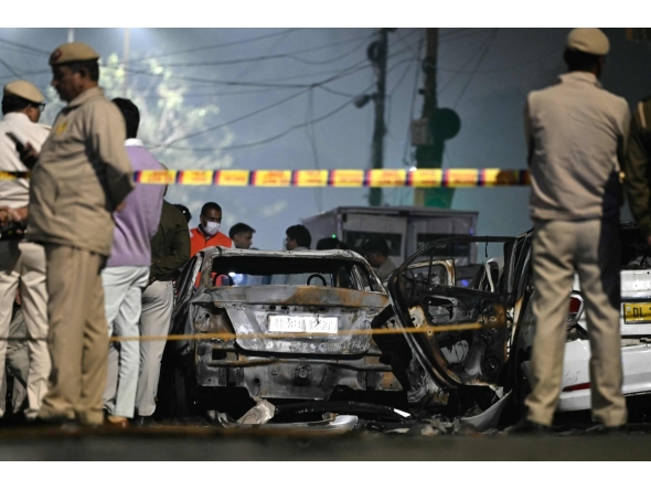 Security personnel stand beside charred vehicles at the blast site after an explosion near the Red Fort in the old quarters of Delhi on November 10, 2025. (Photo by Sajjad HUSSAIN / AFP)
