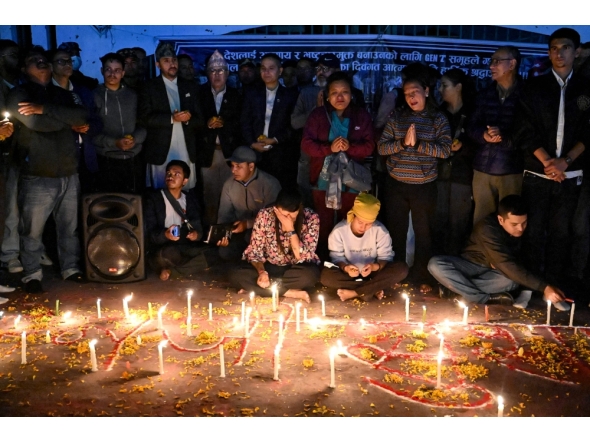 Family members of those killed in September anti-corruption protests take part in a candlelight vigil in front of the fire-damaged parliament building in Kathmandu on November 9, 2025. (Photo by Prakash Mathema / AFP)
