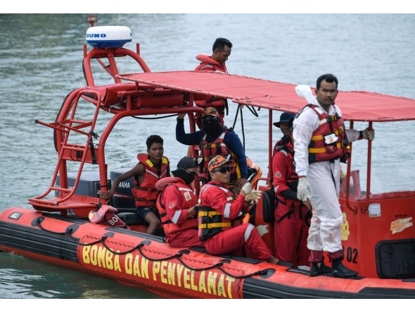 Malaysian rescuers approach a jetty after rescuing Rohingya migrant Iman Shorif (L), days after his boat carrying migrants from Myanmar capsized near the Malaysia-Thailand border, in Langkawi on November 11, 2025. (Photo by Hakim Mustapha / AFP)