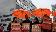 Staff members hold placards as they stand on a picket line on the first day of a five-day resident doctors' strike outside St Thomas' Hospital in central London on November 14, 2025. (Photo by CARLOS JASSO / AFP)