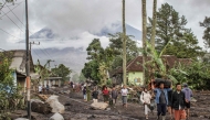 People walk on ground covered in volcanic ash after a pyroclastic flow during yesterday痴 eruption of Mount Semeru in Supiturang village, Lumajang, East Java on November 20, 2025. (Photo by Agus Harianto / AFP)
 