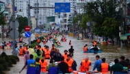 This photo taken on November 20, 2025 shows people wading through floodwaters in Nha Trang in Vietnam's coastal province of Khanh Hoa. (Photo by Duc Thao / AFP)