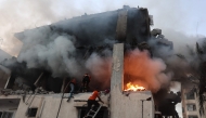 Civil defence personnel search a burning house targeted by Israeli airstrikes in Gaza City, on November 22, 2025. (Photo by Omar AL-QATTAA / AFP)