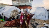 Palestinian children move mattresses to protect them from the rain at a makeshift camp housing displaced Palestinians in Deir al-Balah on November 25, 2025. (Photo by Bashar Taleb / AFP)