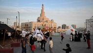 Children and passersby stop to watch men in traditional garb on horseback at the historic Souq Waqif in Qatar on November 26, 2025. (Photo by Mahmud Hams / AFP)