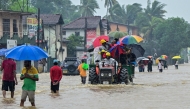 People move through a flooded road after heavy rainfall in Kaduwela on the outskirts of Colombo on November 28, 2025.  (Photo by Ishara S. Kodikara / AFP)