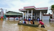 People ride a boat across a flooded street in Ambatale on the outskirts of Colombo on November 29, 2025. (Photo by Ishara S. KODIKARA / AFP)