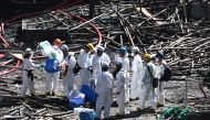 Police officers from the Disaster Victim Identification Unit (DVIU), dressed in white-coloured full-body protective gear, enter one of the housing blocks of Wang Fuk Court in the aftermath of the deadly November 26 fire, in Hong Kong on November 29, 2025. (Photo by Philip FONG / AFP)
