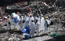 Police officers from the Disaster Victim Identification Unit (DVIU), dressed in white-coloured full-body protective gear, enter one of the housing blocks of Wang Fuk Court in the aftermath of the deadly November 26 fire, in Hong Kong on November 29, 2025. (Photo by Philip FONG / AFP)
