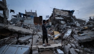 A displaced Palestinian boy stands on the ruins of destroyed buildings in the Bureij refugee camp, in the central Gaza Strip, on November 29, 2025. (Photo by Eyad Baba / AFP)