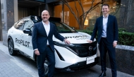 Nissan Motor CEO Ivan Espinosa (L) and Wayve Technologies CEO Alex Kendall (R) pose with a vehicle equipped with the ProPILOT next-generation driver assistance technology system after their signing ceremony in Tokyo on December 10, 2025. (Photo by Kazuhiro Nogi/ AFP)