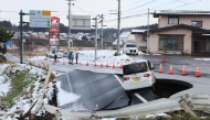 A vehicle rests on the edge of a collapsed road in Tohoku town in Aomori Prefecture on December 9, 2025, following a 7.5 magnitude earthquake off northern Japan. A big quake off northern Japan left at least 30 injured, authorities said on December 9, damaging roads and leaving thousands without power in freezing temperatures. (Photo by JIJI Press / AFP) 