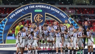 Flamengo's Bruno Henrique lifts the trophy as he celebrates with teammates after wining the FIFA Derby of the Americas match between Cruz Azul and Flamengo at Ahmad Bin Ali Stadium in Doha on December 10, 2025. (Photo by Karim JAAFAR / AFP)
