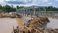 Aerial photo shows residents climbing debris to cross the river on a newly built bridge connecting Aceh and North Sumatra province on December 9, 2025. (Photo by Chaideer Mahyuddin / AFP)