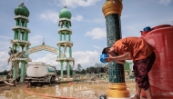 A Muslim man washes his face before attending Friday prayers at Al Ihsan Mosque, which was partially damaged by flooding, in Aceh Tamiang, North Sumatra on December 12, 2025. (Photo by Aditya Aji / AFP)
