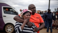 Family members of a victim react at the scene of an attack in Bekkersdal on December 21, 2025. Nine people were killed when gunmen opened fire outside Johannesburg early on December 21, 2025. (Photo by Emmanuel Croset / AFP)