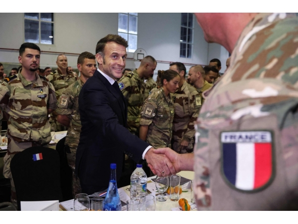 French President Emmanuel Macron shakes hands with a soldier during a Christmas diner with troops of the 5th Cuirassier Regiment's base in Zayed Military City, near Abu Dhabi, on December 21, 2025.(Photo by Ludovic MARIN / AFP)
