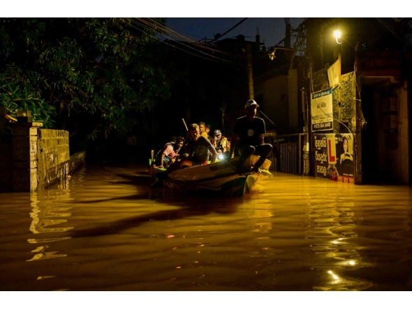 People ride on a boat belonging to Sri Lanka's army at a flooded street after heavy rainfall in Wellampitiya on the outskirts of Colombo on November 30, 2025. (Photo by Ishara S. Kodikara / AFP)