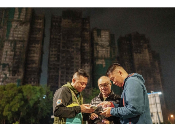 This picture taken on December 10, 2025 shows Yip Ka-kui (C) and his sons Yip Shun-ting (L) and Yip Shun-yin (R) looking at old photographs of his wife Pak Shui-lin. (Photo by Yan Zhao / AFP)