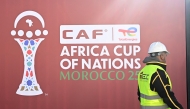 An employee walks past the games' logo outside of the Al-Medina Stadium in Rabat, on December 18, 2025, ahead of the Africa Cup of Nations (AFCON).
