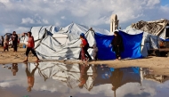 Displaced Palestinians walk past a large pool of rain water accumulated near tent shelters as the region experiences rain and cold winter conditions, in Gaza City on December 28, 2025. Photo by Omar AL-QATTAA / AFP