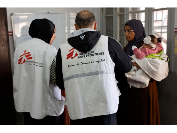 A Palestinian woman arrives with a child at the Doctors Without Borders or Medecins Sans Frontieres (MSF) clinic, in the al-Rimal neighborhood of Gaza City on new year's Eve, December 31, 2025. (Photo by Omar AL-QATTAA / AFP)