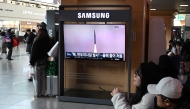 People sit in front of a television screen showing a news broadcast with file footage of a North Korean missile test, at a train station in Seoul on January 4, 2026. Photo by Jung Yeon-je / AFP
