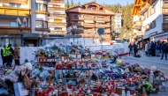 A mourner lays a flower bouquet at a makeshift memorial near the Constellation, on January 4, 2026, in Crans-Montana in honour of the victims of the fire that ripped through the venue in the luxury Alpine ski resort on New Year's Eve. Photo by MAXIME SCHMID / AFP