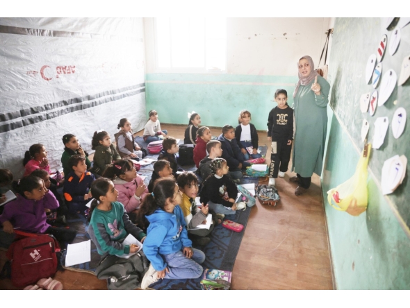 Palestinian children, many of whom are part of displaced families, sit on the floor as they attend class, at the UNRWA Deir Al-Balah Joint School, west of Deir Al-Balah. (AFP)