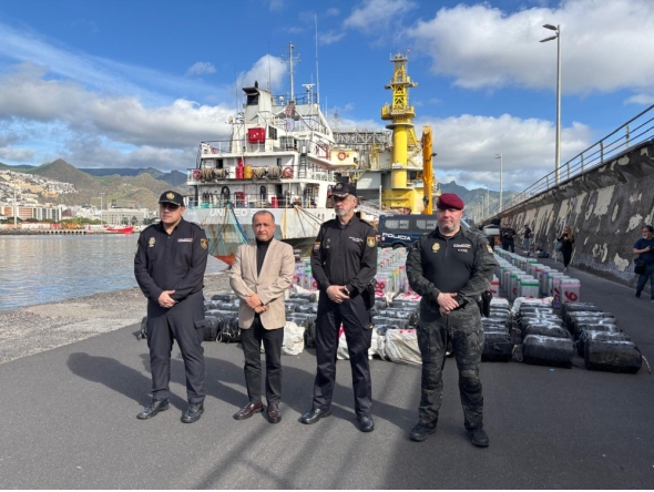 This undated handout photo released on January 12, 2026 by Spanish National Police shows Spanish police posing in front of some of the nearly 10 tons of cocaine seized on a cargo ship in Spain's Canary Islands. (Photo by Handout / Spanish National Police / AFP)