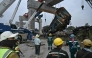 Recovery workers watch as a carriage of a train that crashed when a construction crane collapsed is lifted off the tracks in Thailand's Nakhon Ratchasima province on January 14, 2026. (Photo by Lillian Suwanrumpha / AFP)
 